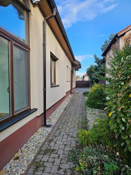 REZERVOVANÉ! Predáme 5-izbový rodinný dom na Štúrovej ulici, Vráble - Pohľad na bočnú časť rodinného domu v Štúrovej ulici vo Vrábľoch s dláždeným chodníkom.