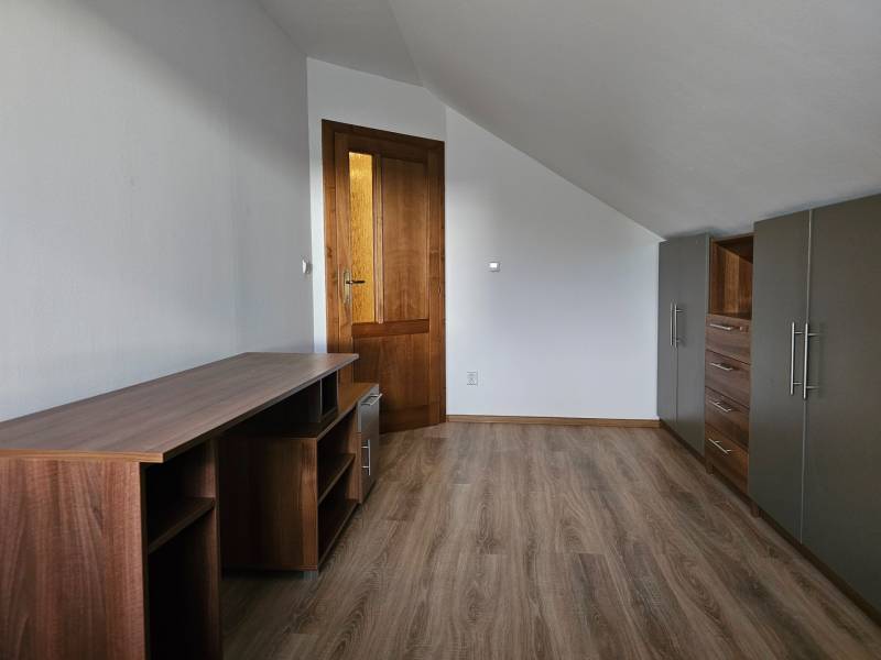 REZERVOVANÉ! Predáme 5-izbový rodinný dom na Štúrovej ulici, Vráble - Izba v rodinnom dome s nábytkom, bielymi stenami a podlahou s dreveným dekorom.