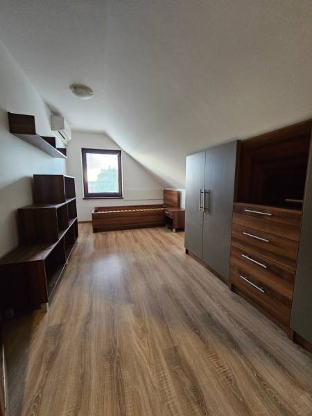 REZERVOVANÉ! Predáme 5-izbový rodinný dom na Štúrovej ulici, Vráble - Podkrovie rodinného domu s nábytkom, podlahou s dreveným dekorom a oknom.