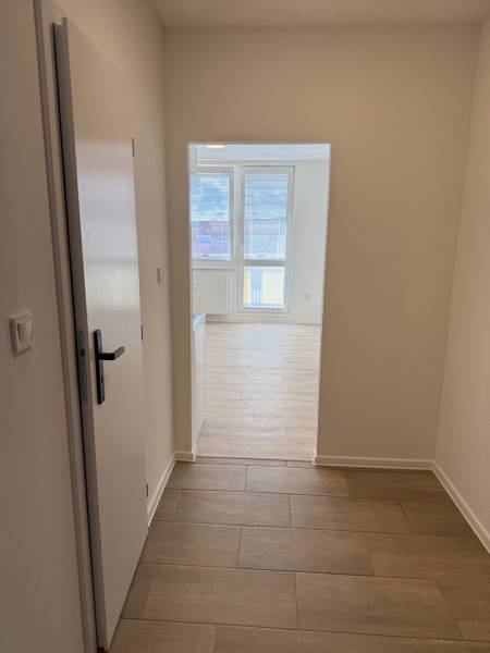  Prenájom garsónky po kompletnej rekonštrukcii (možnosť odkúpenia) - Garsónka s podlahou s dreveným dekorom a veľkými oknami poskytuje svetlý interiér.