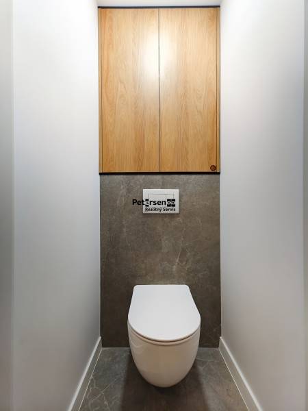 Prenájom úplne nového 2 izb. bytu - skvelá poloha a komfortné bývanie. - Toaleta v 2-izbovom byte s podlahou z tmavého kameňa a drevenými skrinkami.