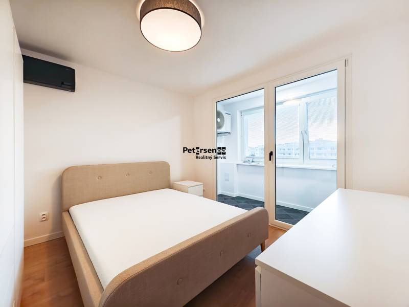 Prenájom úplne nového 2 izb. bytu - skvelá poloha a komfortné bývanie. - Spálňa v 2-izbovom byte s posteľou, stolíkom a balkónom, podlaha s dreveným dekorom.