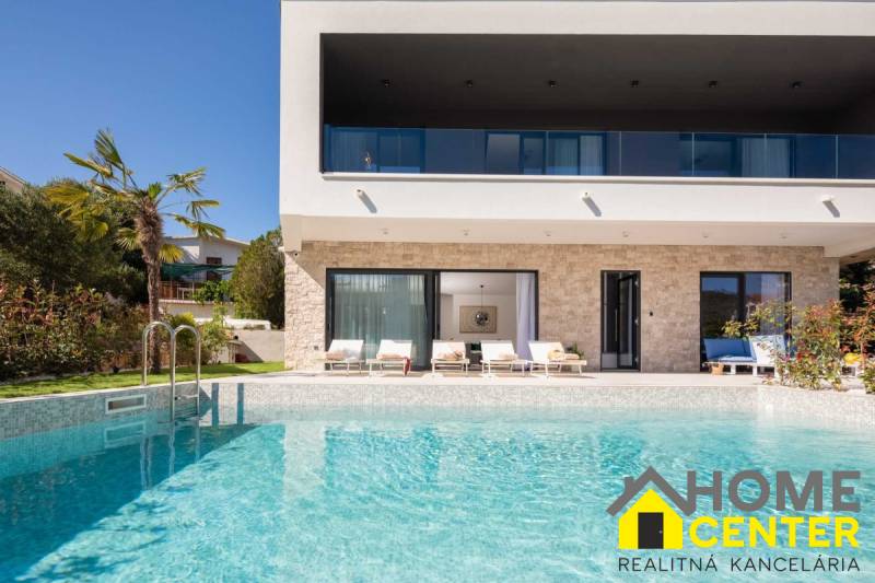 NA PREDAJ novo postavená VILA  /200 m2/ pri mori, Rogoznica - Vila v Bale s bazénom, palmami, terasou a ležadlami na pozadí.