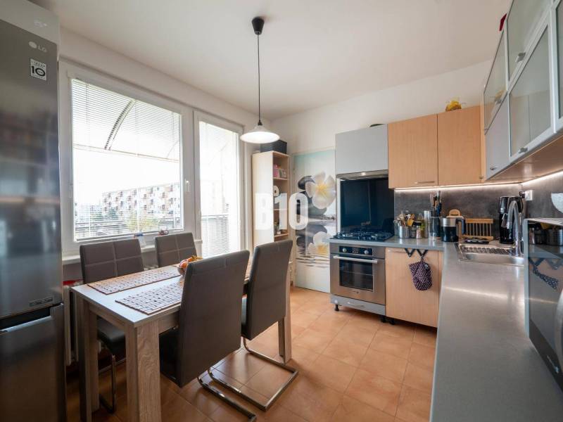 Príjemný 4 izbový byt s balkónom - Klokočina - Kuchyňa v 4-izbovom byte s jedálenským stolom, hnedými stoličkami a veľkým oknom.