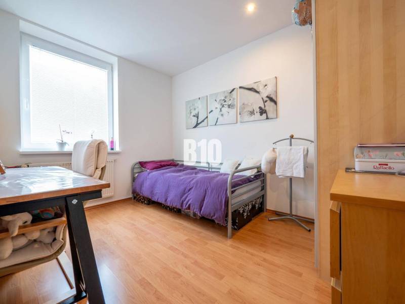 Príjemný 4 izbový byt s balkónom - Klokočina - Spálňa v 4-izbovom byte s podlahou s dreveným dekorom a fialovým prehozom.