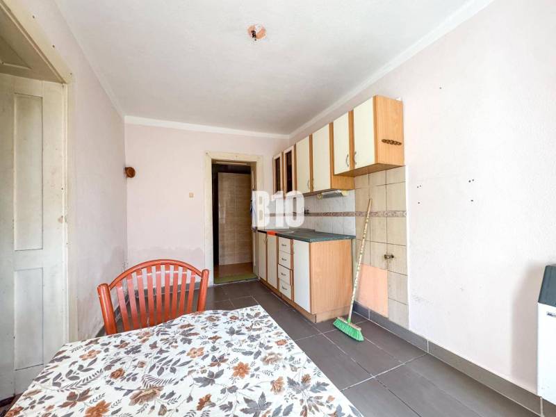 Rodinný dom s veľkým pozemkom (4641 m2)  - Ondrejovce - Kuchyňa s jednoduchými skrinkami, kachličkami a stolom v rodinnom dome.