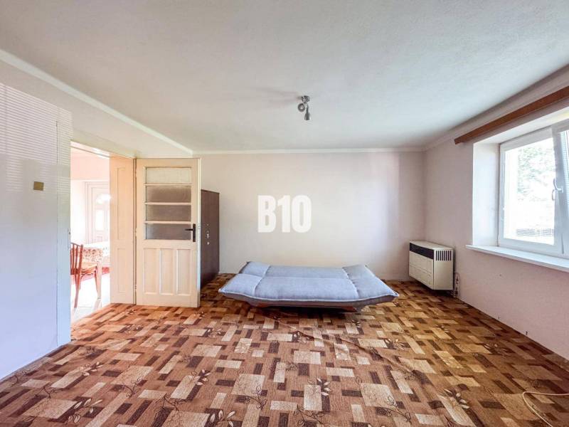 Rodinný dom s veľkým pozemkom (4641 m2)  - Ondrejovce - Obývačka v rodinnom dome s podlahou s dreveným dekorom a pohovkou.