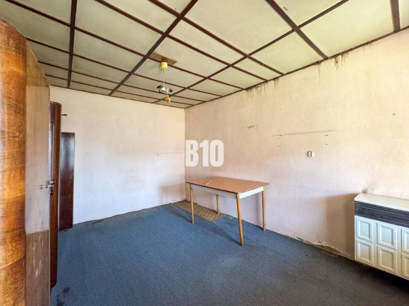 Rodinný dom s veľkým pozemkom (4641 m2)  - Ondrejovce - Interiér izby v rodinnom dome, obsahujúci koberec, skrine a stôl.