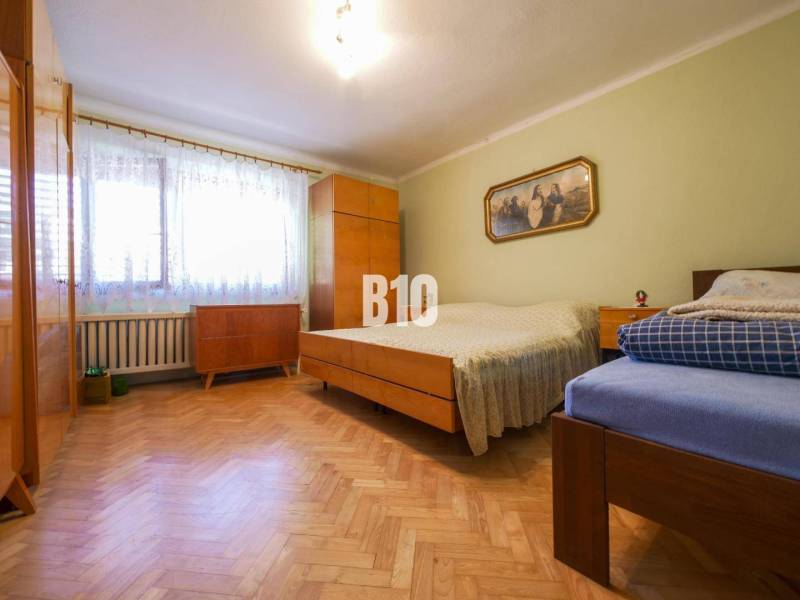 Rodinný dom s krásnym veľkým pozemkom ( stavebným) - Nové Sady - Spálňa s drevenou podlahou a jednoduchým nábytkom v rodinnom dome.