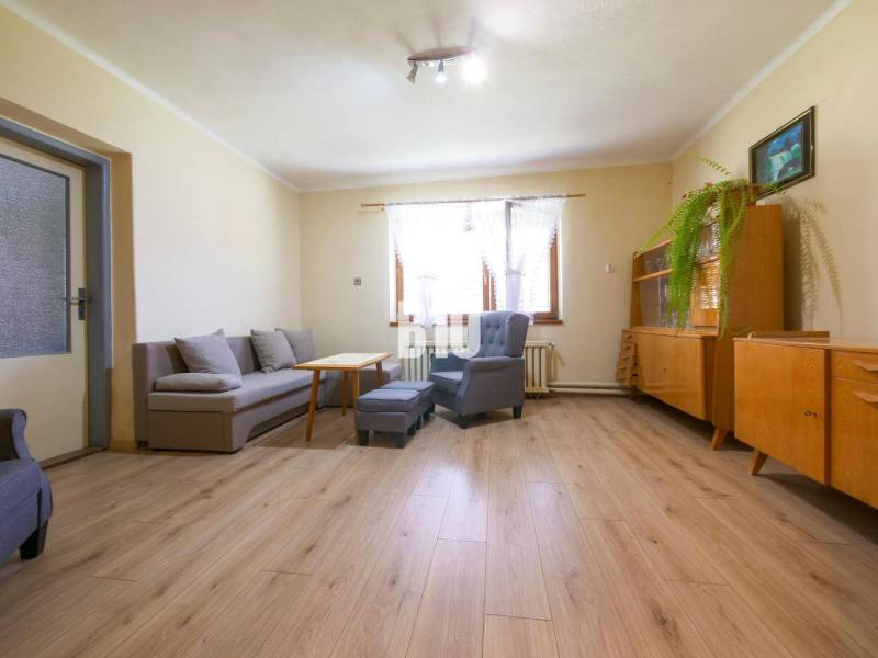 Rodinný dom s krásnym veľkým pozemkom ( stavebným) - Nové Sady - Obývačka v rodinnom dome s dreveným nábytkom, sivým gaučom a svetlým podlahovým obložením.