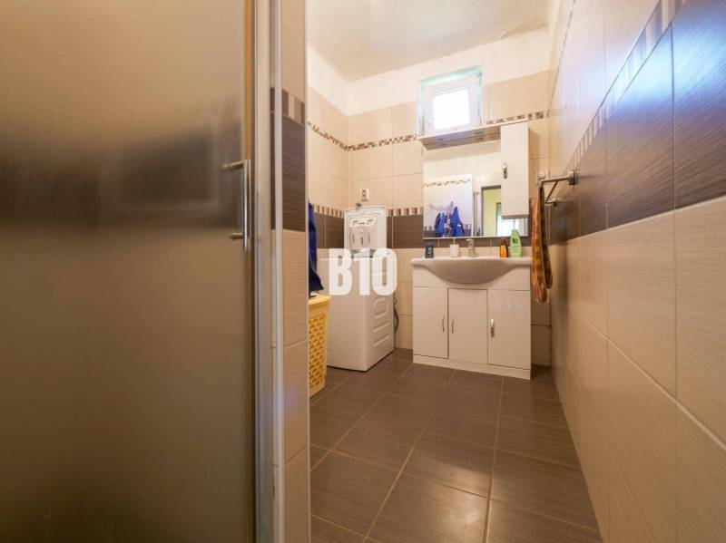 Rodinný dom s krásnym veľkým pozemkom ( stavebným) - Nové Sady - Kúpeľňa v rodinnom dome s práčkou a umývadlom, obložená hnedými dlaždicami.