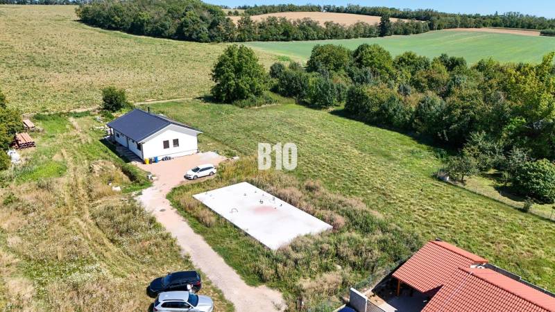 Základová doska na  575 m2 pozemku - Čeľadice - Záber na pozemok pre bývanie v Čeľadiciach zahŕňa dom, zeleň a autá.