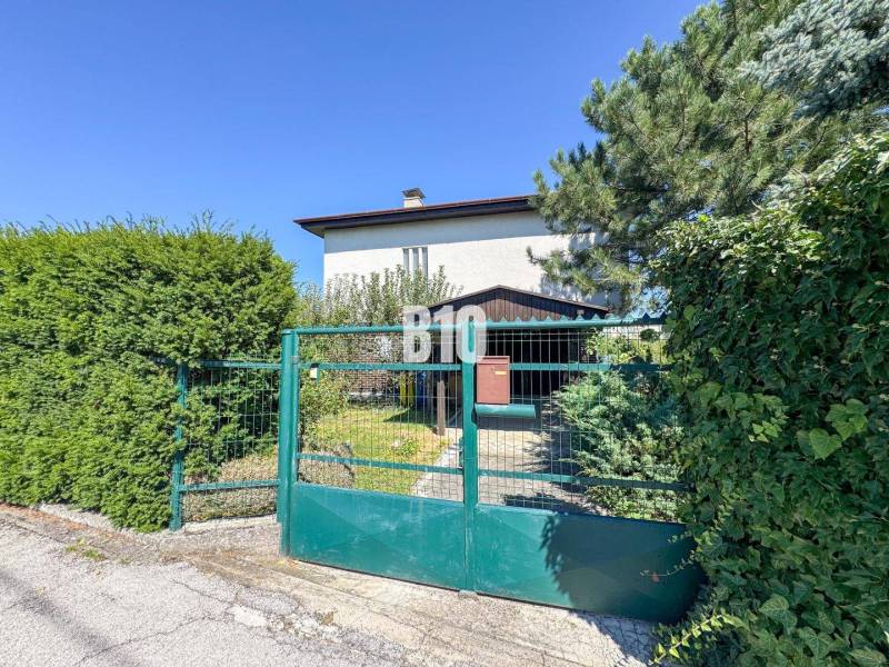 Rodinný dom s nádherným 8 árovým pozemkom na Kamennej ulici - Rodinný dom na Kamennej ulici v Nitre so záhradnou bránou a zeleňou.