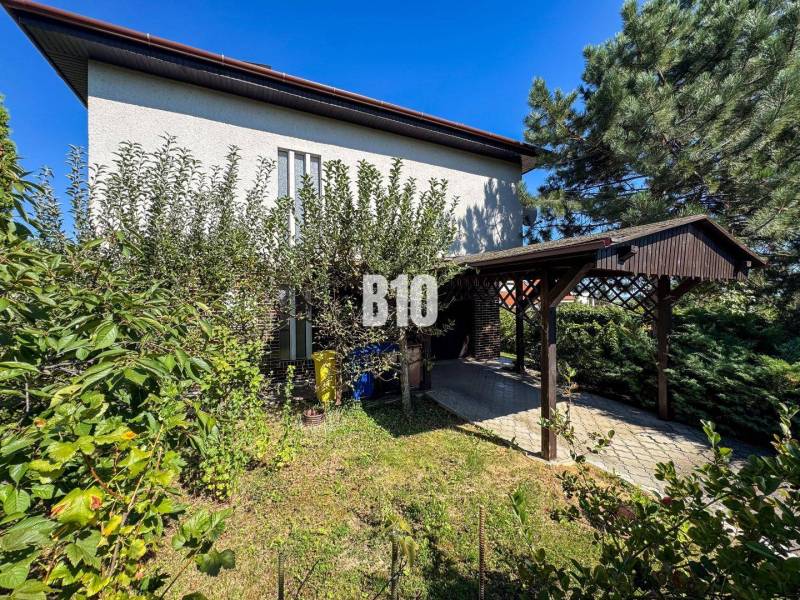 Rodinný dom s nádherným 8 árovým pozemkom na Kamennej ulici - Rodinný dom na Kamennej ulici v Nitre obklopený zeleňou a prístreškom pre auto.