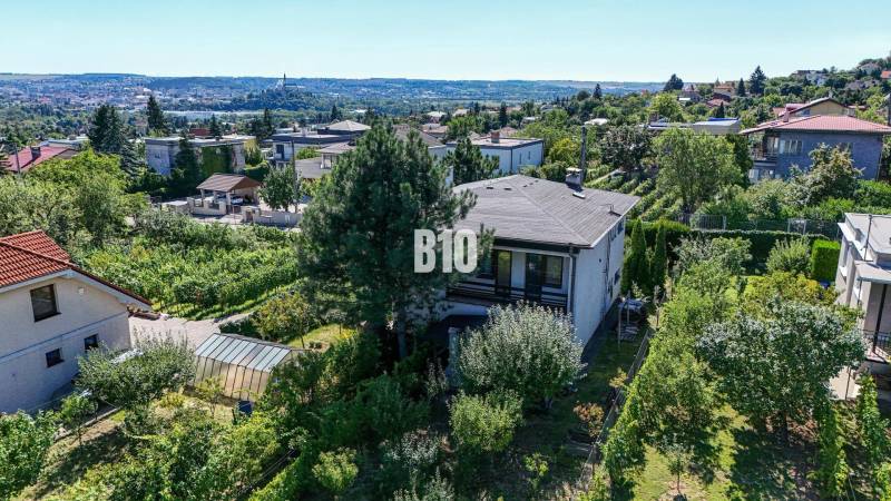 Rodinný dom s nádherným 8 árovým pozemkom na Kamennej ulici - Pohľad na rodinný dom na ulici Kamenná v Nitre obklopený zeleňou a mestskou panorámou.