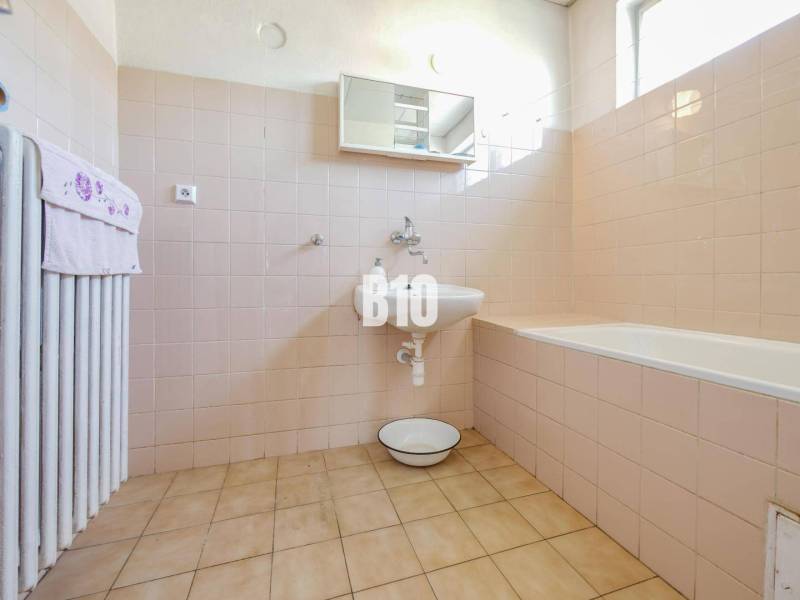 Rodinný dom s nádherným 8 árovým pozemkom na Kamennej ulici - Kúpeľňa v rodinnom dome s vaňou a svetlými obkladmi na stenách.