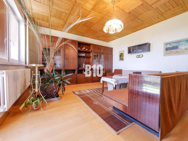 Rodinný dom s nádherným 8 árovým pozemkom na Kamennej ulici - Obývačka v rodinnom dome s podlahou s dreveným dekorom a dreveným stropom.