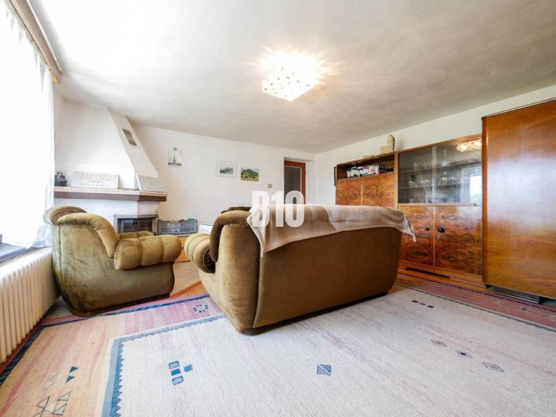 Rodinný dom s nádherným 8 árovým pozemkom na Kamennej ulici - Obývacia izba s krbom a retro nábytkom v rodinnom dome, podlaha s dreveným dekorom.