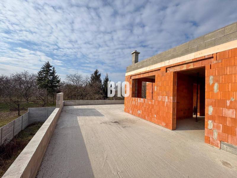 6 izbový rodinný dom  - DVOJGARÁŽ - CABAJ časť Riegler - Rodinný dom vo výstavbe s terasou na veľkom dvore, obklopený prírodou a stromami.