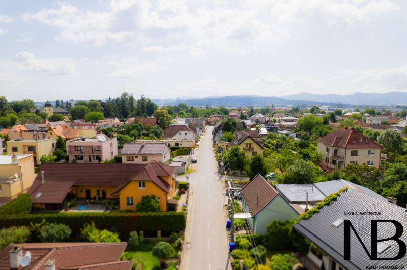 Na predaj rodinný dom s podnikateľským potenciálom, TN-Záblatie - Ulica Záblatská v Trenčíne s rodinnými domami obklopenými zeleňou a modrou oblohou.