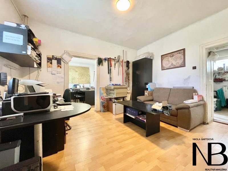 Na predaj rodinný dom s podnikateľským potenciálom, TN-Záblatie - Izba v rodinnom dome so sedačkou, stolom a kancelárskym vybavením na drevenej podlahe.