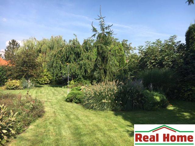 Dom s garážou na peknom rovinatom pozemku so šírkou 24m. - Záhrada pri rodinnom dome v Čiernej Vode s bujnou zeleňou a trávnikom.