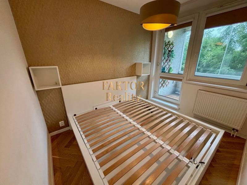 2-izbový byt po kompletnej rekonštrukcii Staré mesto - Spálňa s posteľou a veľkým oknom, 2-izbový byt s podlahou s dreveným dekorom.