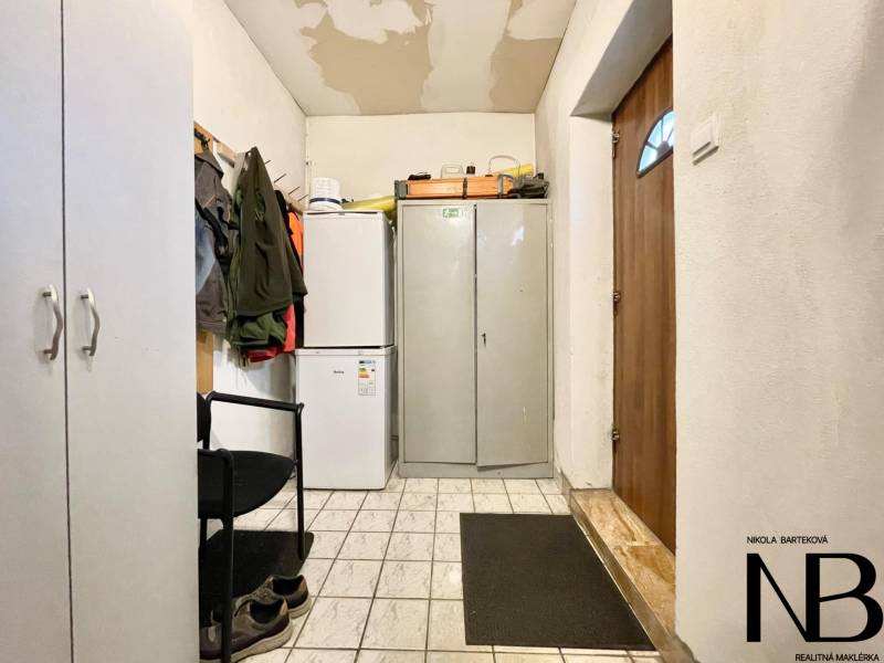 Na predaj objekt vhodný na podnikanie – Trenčín, Záblatie - Interiér rodinného domu s chladničkou, skriňou a bundami na vešiaku.