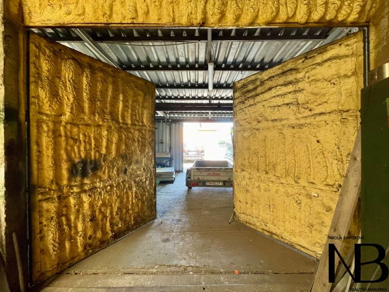 Na predaj objekt vhodný na podnikanie – Trenčín, Záblatie - Obchodné priestory s otvorenými dverami a kovovou strechou, v pozadí vidieť auto.