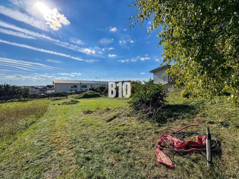 Stavebný pozemok so stavebným povolením - Janíkovce - 729 m2 - Pozemok na bývanie v Nitre, trávnatá plocha so zeleňou a slnečnou oblohou.