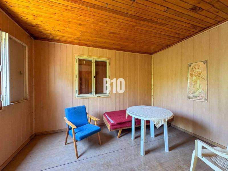 Vinica na skok od Nitry + chata - 590 m2 - Drevený interiér s kreslom, stolíkom a obrazom, ideálny pre Vinice.