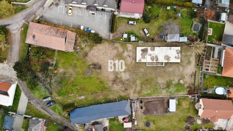 1786 m2 - základová doska - stavebné povolenie + projekt - Mojmírovce - Letecký pohľad na pozemok, s budovou a parkovacími miestami, ideálny pre bývanie.