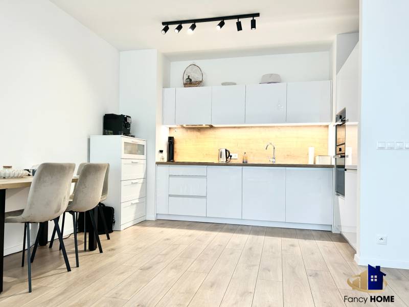 PRENÁJOM exkluzívny 2 izb byt POPRAD s loggiou 53,9 + 8,34 m2 - Kuchyňa v 2-izbovom byte s podlahou s dreveným dekorom a jedálenským stolom.