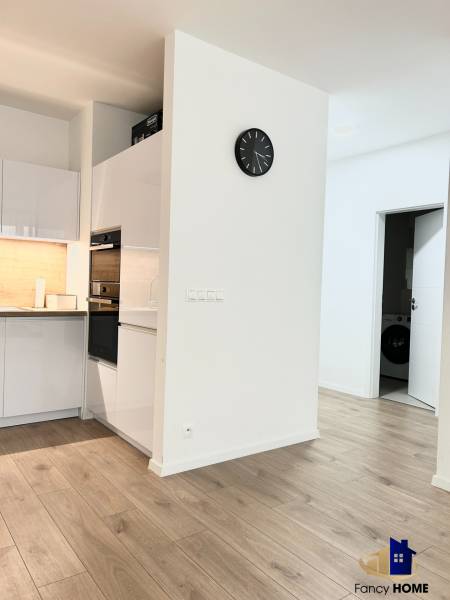 PRENÁJOM exkluzívny 2 izb byt POPRAD s loggiou 53,9 + 8,34 m2 - Kuchyňa v 2-izbovom byte s dreveným dekorom podlahy a bielym nábytkom.