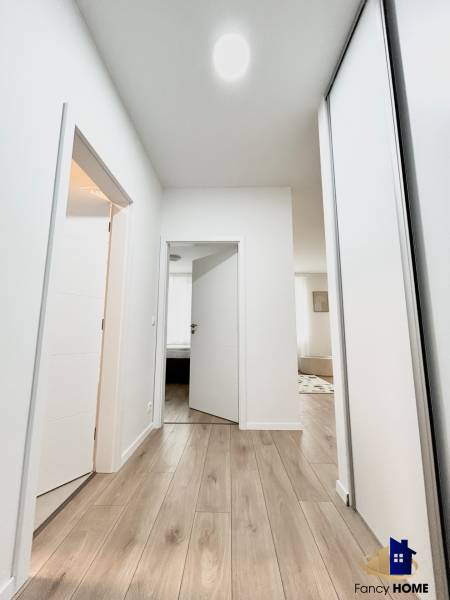 PRENÁJOM exkluzívny 2 izb byt POPRAD s loggiou 53,9 + 8,34 m2 - Chodba so svetlými stenami a podlahou s dreveným dekorom, vedúca do miestností 2-izbového bytu.
