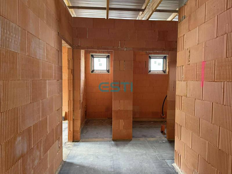 Rodinný dom - bungalov, Teplička nad Váhom - Interiér rodinného domu s priečkami z tehál, dve malé okná, betónová podlaha.