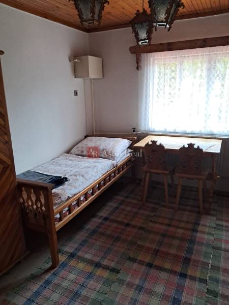 CHALUPA v rekreačnej oblasti TERCHOVÁ - ZÁZRIVÁ  - Izba v rodinnom dome s posteľou, oknom, stolom a stoličkami.