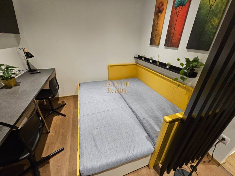 Kompletne zrekonštruovaná garsónka - BA Nové mesto - Garsónka s posteľou, stolom, kreslami a dekoratívnymi obrazmi, podlaha s dreveným dekorom.