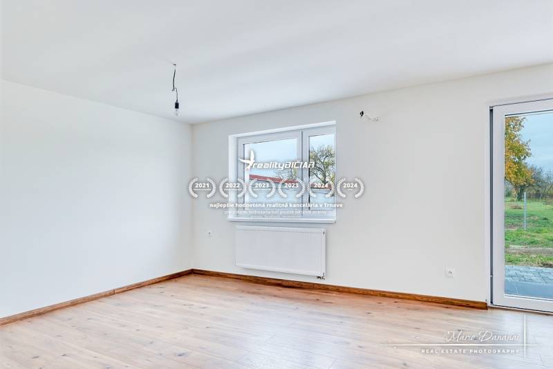 3-izbový moderne zrekonštruovaný rodinný dom v obci Jaslovské Bohunice - Priestranná miestnosť v rodinnom dome s podlahou s dreveným dekorom a veľkými oknami.