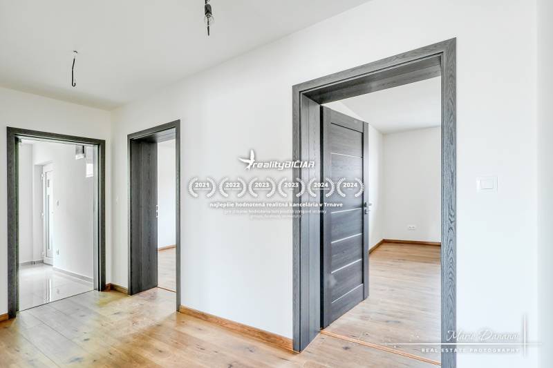 3-izbový moderne zrekonštruovaný rodinný dom v obci Jaslovské Bohunice - Interiér rodinného domu s podlahou s dreveným dekorom a bielymi stenami.