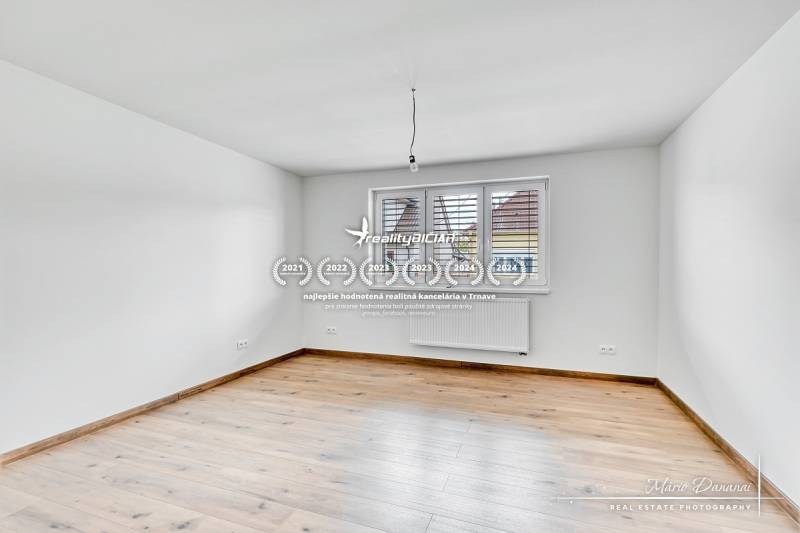 3-izbový moderne zrekonštruovaný rodinný dom v obci Jaslovské Bohunice - Prázdna izba v rodinnom dome s podlahou s dreveným dekorom a bielymi stenami.