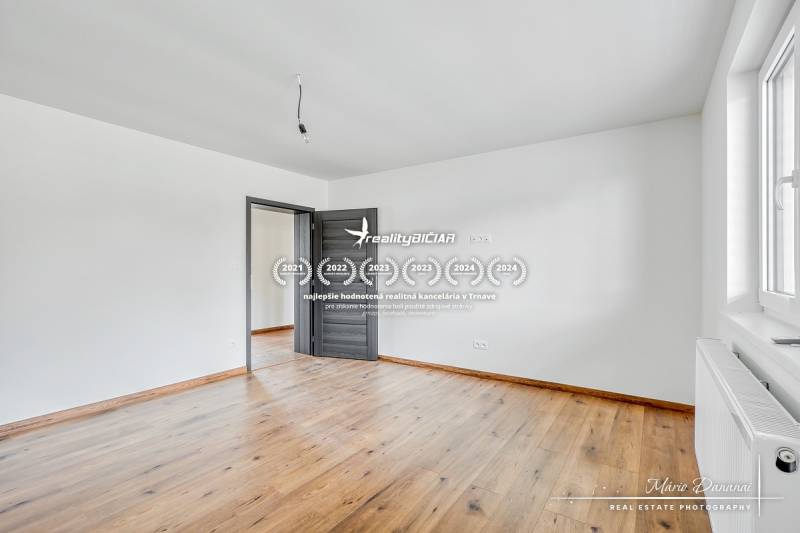 3-izbový moderne zrekonštruovaný rodinný dom v obci Jaslovské Bohunice - Izba v rodinnom dome s bielymi stenami a podlahou s dreveným dekorom.