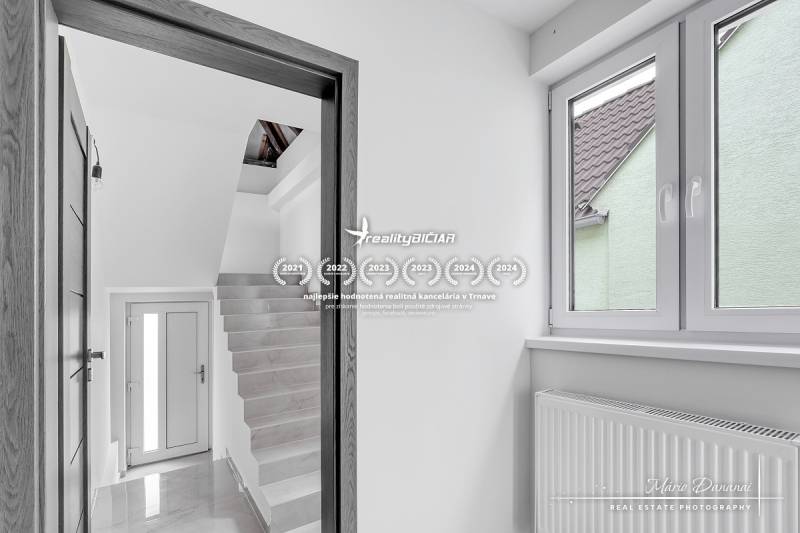 3-izbový moderne zrekonštruovaný rodinný dom v obci Jaslovské Bohunice - Interiér rodinného domu s bielymi stenami, schodiskom a veľkým oknom.