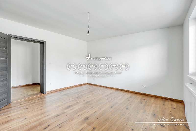 3-izbový moderne zrekonštruovaný rodinný dom v obci Jaslovské Bohunice - Izba s bielymi stenami a podlahou s dreveným dekorom v rodinnom dome.