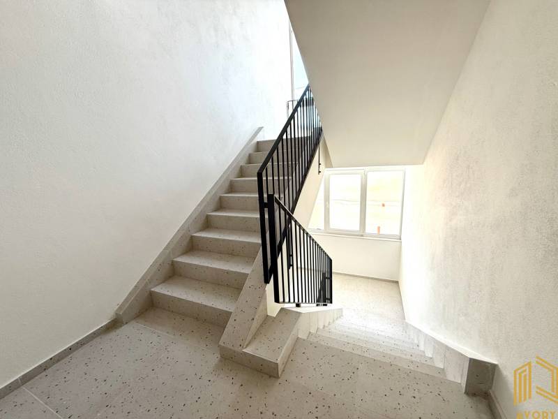 NOVÝ 2 - IZB. BYT (63m2), SENICA - SADOVÁ - Schodisko v bytovom dome s oknom, biele steny a dlažba.