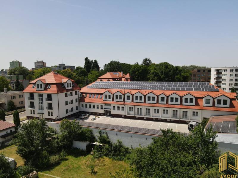 NOVÝ 2 - IZB. BYT (63m2), SENICA - SADOVÁ - Budova na Sadovej ulici v Senici s červenou strechou a solárnymi panelmi.