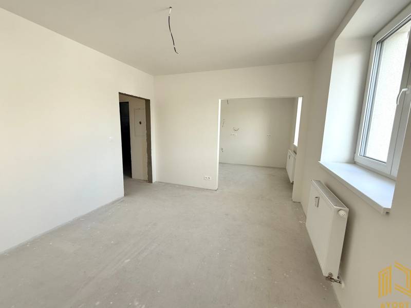 NOVÝ 2 - IZB. BYT (63m2), SENICA - SADOVÁ - Svetlá miestnosť, priestranné okno, biele steny a radiátor v 2-izbovom byte.