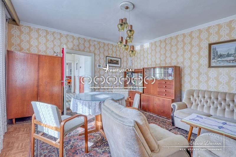 REZERVOVANÉ Starší 2-izbový rodinný dom v obci Dobrá Voda - Obývacia izba v rodinnom dome s retro nábytkom a podlahou s dreveným dekorom.