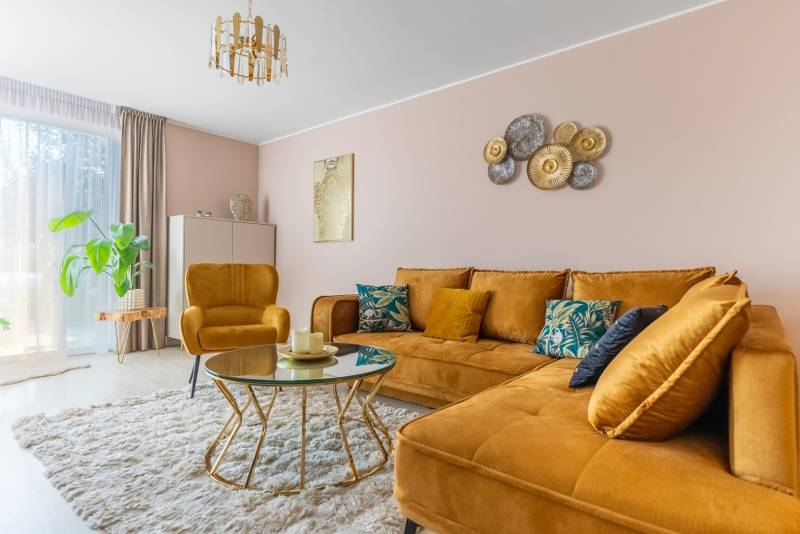 Moderný rodinný dom s bazénom v Trnave!!! - Obývacia izba v rodinnom dome s horčicovou sedačkou a stolíkom na podlahe s dreveným dekorom.