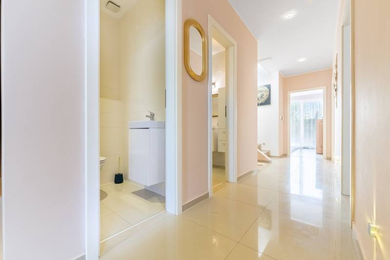 Moderný rodinný dom s bazénom v Trnave!!! - Chodba v Rodinnom dome so svetlými dlaždicami, otvorené dvere do kúpeľne, zrkadlo na stene.